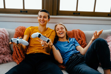 Young woman winning video game, friend laughing. Cheerful Togetherness in a Domestic Room
