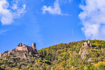 Obraz premium front view, far distance of, a castle ruins on hugh rock hill, with second castle, against blue sky