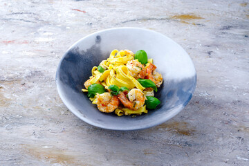 Traditionelle italienische Tagliatelle ai gamberoni Nudeln mit Riesengarnelen und Kräutern serviert als close-up auf einem Design Teller mit Textfreiraum