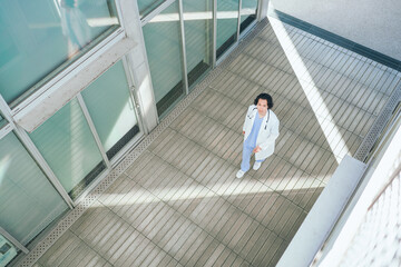 病院の廊下を歩くスクラブ白衣を着た若い男性医師