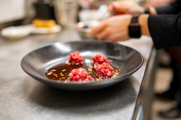 professional chef's hands cooking Raw beef meat tartar in restaurant kitchen