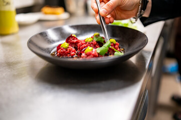 professional chef's hands cooking Raw beef meat tartar in restaurant kitchen