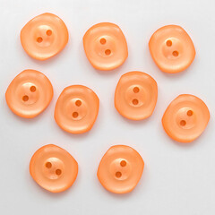 Peach color plastic sewing buttons on a white background.