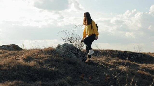 Woman hiker with a backpack tries to catch the signal of her mobile phone in the mountains, climbs the highest rock, but there is no signal