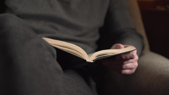 a young man in a gray sweater makes an entry in his diary. armchair. close-up.