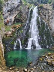 Fototapeta premium Waterfall cascading in green pond, Gollinger waterfall in Golling near Salzburg, Austria. Stunning view of cascade waterfall over mossy rocks in the Alps with long exposure