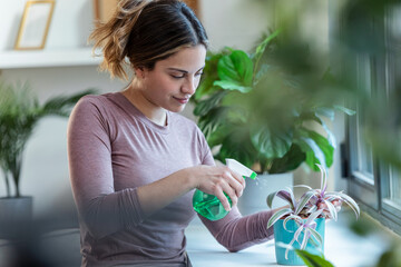 Beautiful smiling woman arranging plants and flowers at home