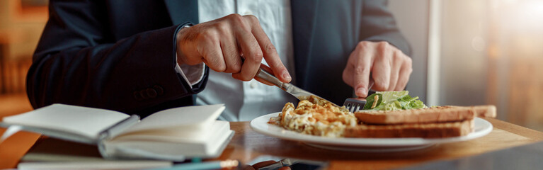 Close up of businessman taking a breakfast before starting working day in cafe