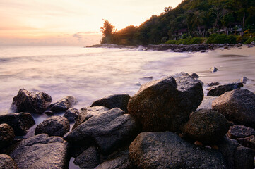 Beautiful landscape with colorful sunset on the sea rock beach.
