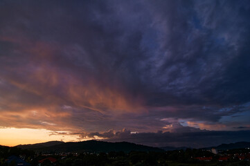 Dramatic landscape with view on evening city. Beautiful cloudy sky.