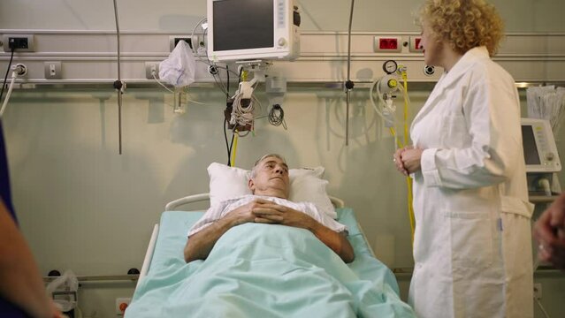 Slow-motion shot of a doctor interacting with sick patient during clinical consultation in hospital ward