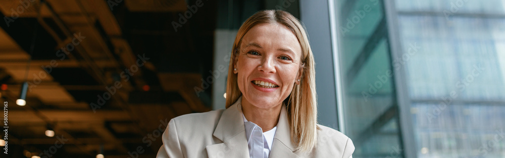 Wall mural smiling businesswoman making notes and talks to camera while working in cafe