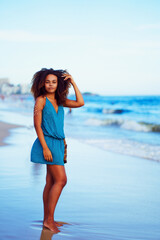 full body portrait beautiful young black brazilian woman standing on the shore of the beach in...