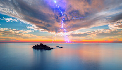 Naklejka na ściany i meble Beautiful landscape with lightning over the calm sea at sunset 