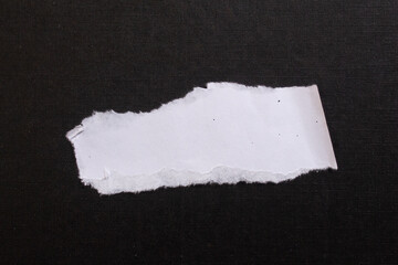 White torn paper piece isolated on black background
