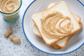 Plate with peanut butter sandwiches on a light-grey granite background, selective focus, middle close-up, horizontal shot