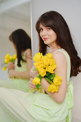 beautiful gentle young woman brunette with a bouquet of yellow tulips. 