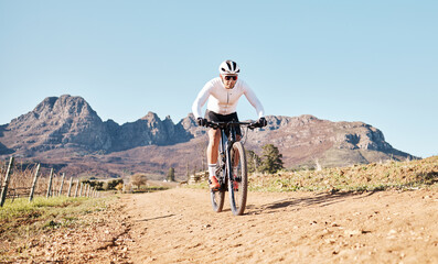Man, mountains and cycling on trail in nature, countryside and blue sky for triathlon sports in...