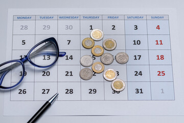 Kartka z kalendarza a na niej leżące okulary, rozrzucone polskie monety i dlugopis © Paweł Kacperek