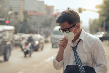 Business man wearing a mask and coughing on the street. Protection against air pollution and dust...