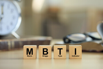 wooden blocks with the letters MBTI on the table with books.Psychological study and research concept.Personality typology. Psychology test for human types.MBTI - Myers-Briggs Type Indicator - obrazy, fototapety, plakaty