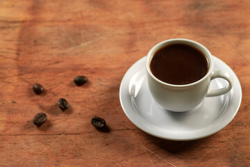 Coffee cup and coffee beans on wooden table. Black background.