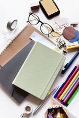 A variety of stationery on the white desk - a mint-colored diary top view with pens, notebooks,...