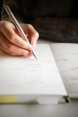 A female college student who holds a silver pen in her hand and records her schedule, daily plans,...