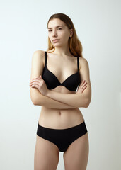 Fototapeta premium beautiful woman posing in a black swimsuit on a light background