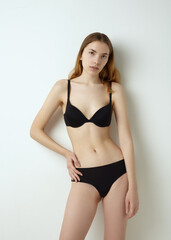 Obraz premium beautiful woman posing in a black swimsuit on a light background