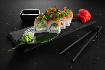 Set of sushi with red fish, caviar, seaweed, cheese and kiwi on a black background. Japanese cuisine. restaurant menu