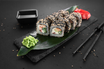 California sake roll with salmon, avocado and sesame. Traditional Japanese cuisine, sushi rolls on a black background