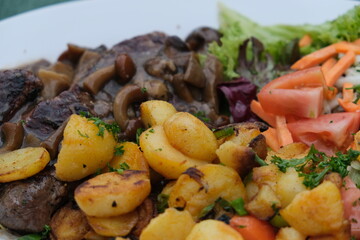 Dish made of fried potatos, mushrooms and fresh vegitables on a plate