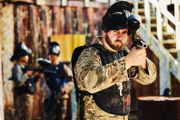 Fototapeta na wymiar Paintball, target or portrait of man with gun in shooting game playing in action battlefield mission. War, hero or focused soldier with army weapons gear in survival military challenge competition