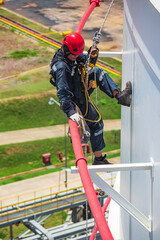 Focus male worker inspection wearing safety first harness rope safety line working at a high tank roof place on pipe