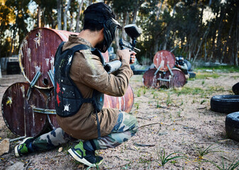 Fototapeta premium Paintball, gun and shooting with a sports man on a battlefield for military or war training for the army. Fitness, team building and safety with a male athlete or soldier playing a game outdoor