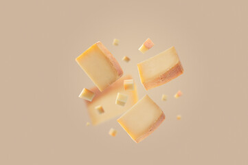 Pieces of hard cheese flying in the air. Falling isolated cheese on light beige background with copy space