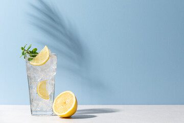Refreshing drink with ice, lemon and mint. Cold lemonade on blue background