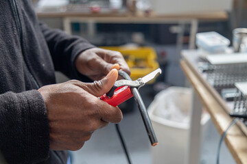 Closeup of a man stripping a cable with a wire stripper