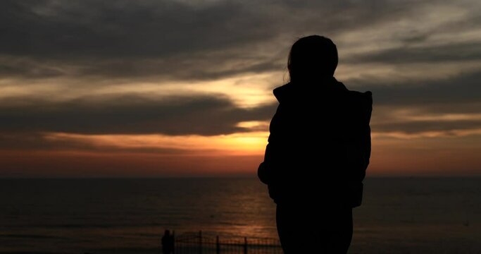 Silhouette of woman looking at the beautiful sunrise over the sea