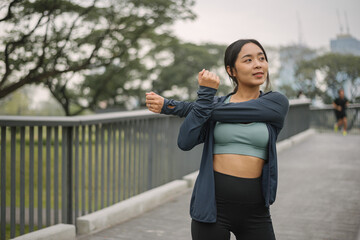 Asian happy woman exercise in park on morning. Healthy female wearing sportswear and stretching...