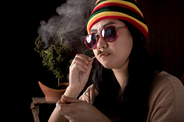 Beautiful Asia women smoking weed at cannabis tree background