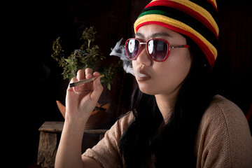 Beautiful Asia women smoking cigarettes at cannabis tree background