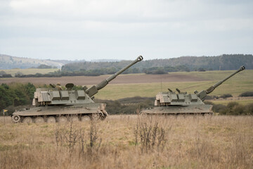 Fototapeta premium Two British army military AS90 (AS-90 Braveheart Gun Equipment 155mm L131) armoured self-propelled howitzers, guns skywards, on a military exercise, Wilts UK