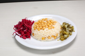 Rice with chickpeas served cucumber pikles and black cabbage