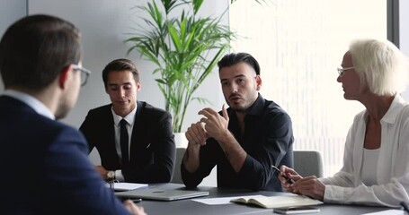 Meeting of shareholders in modern boardroom, led by serious millennial businessman make speech, provide information at formal group appointment in company office. Seminar, corporate training, business