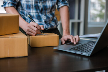 Small business entrepreneur, SME, freelance male working with boxes at home. Use a laptop for...