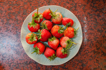 On the table are fresh strawberries in a beautiful dish.