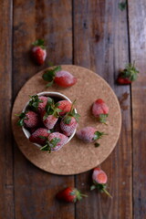 cold strawberries in a bowl on wooden mat top view