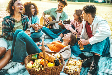 Cheerful young people having picnic party outdoors - Happy friends group having fun singing and...